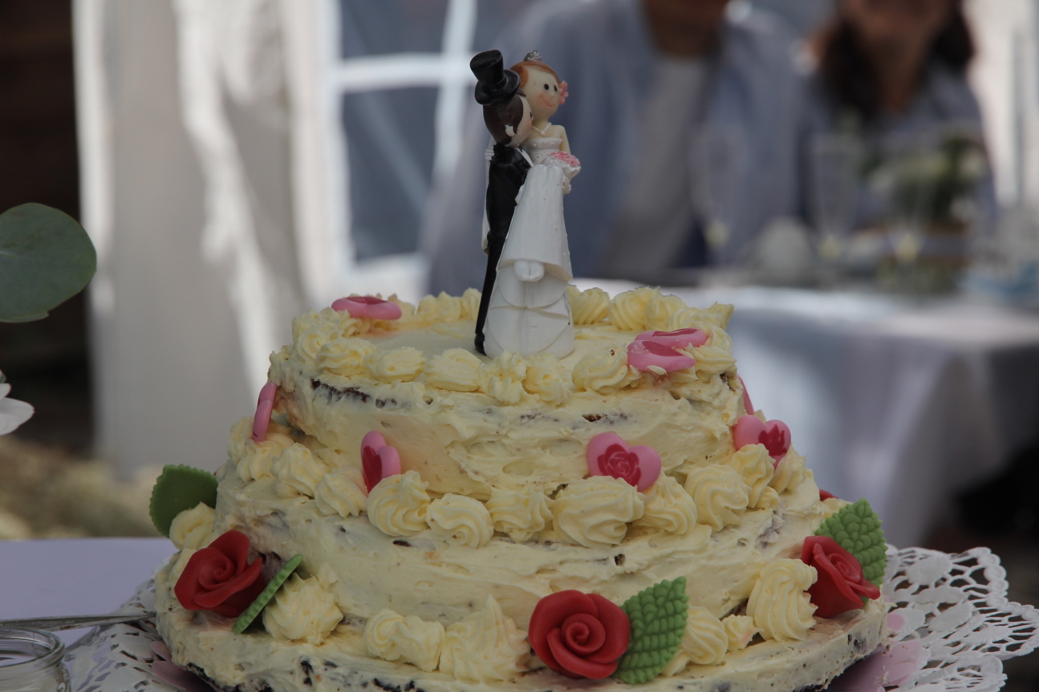 Wedding cake decorated with flowers and a bride and groom topper