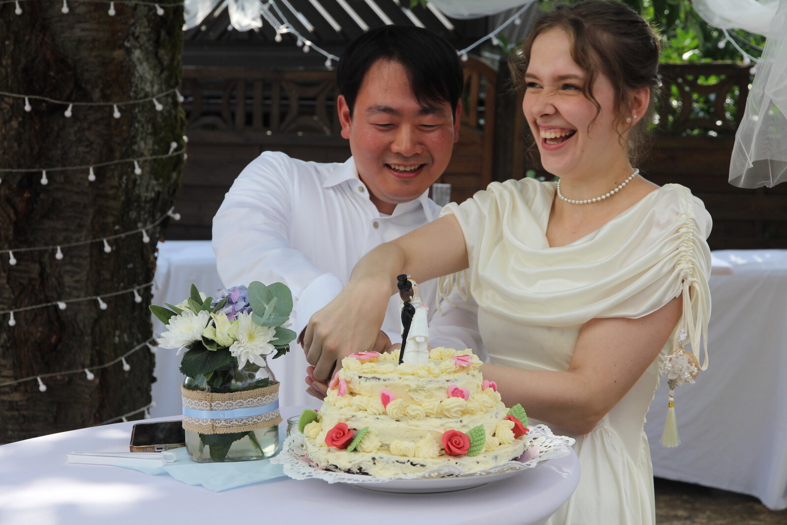 Yongjai and Vanessa laughing together as they cut their wedding cake