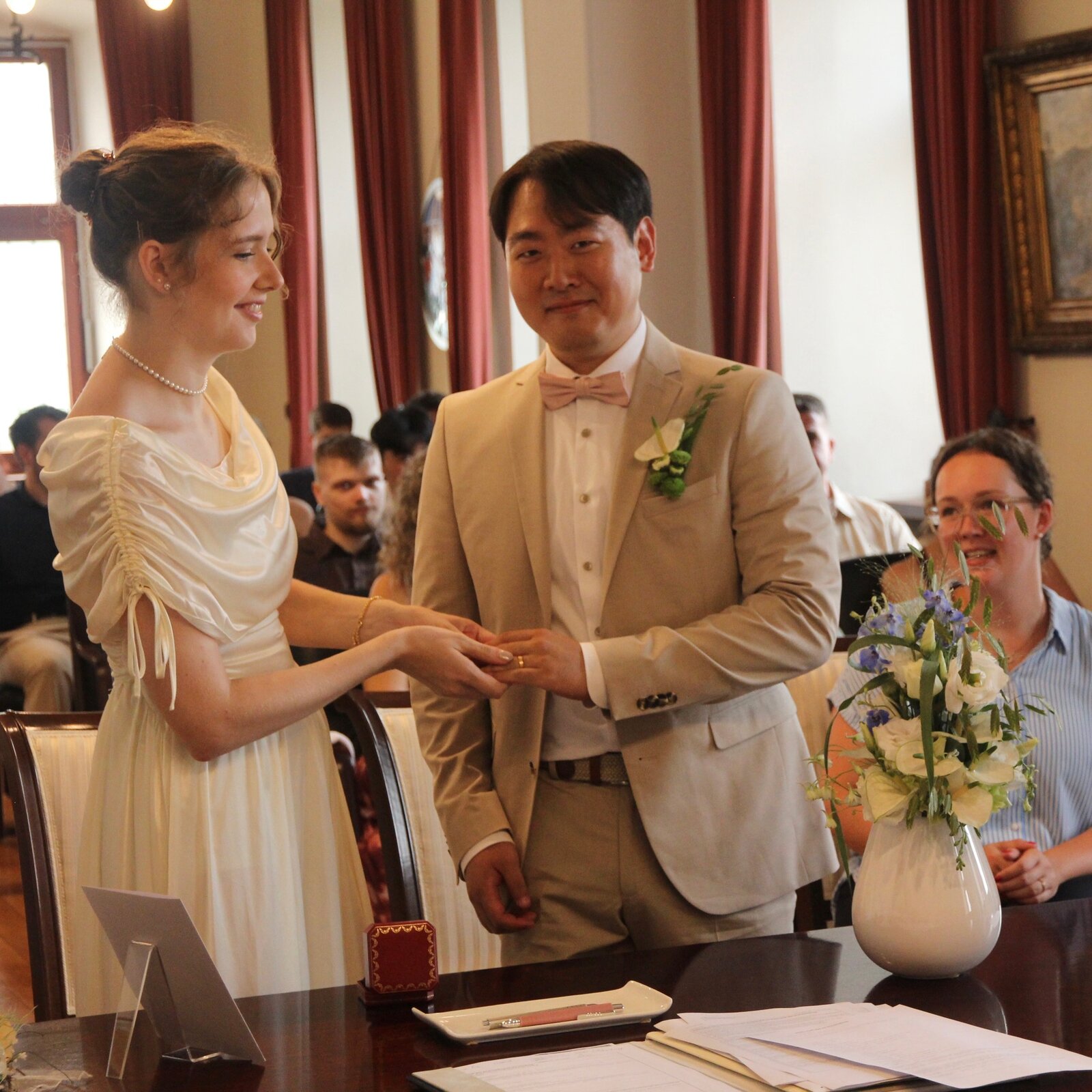Vanessa placing a ring on Yongjai’s hand during the ceremony