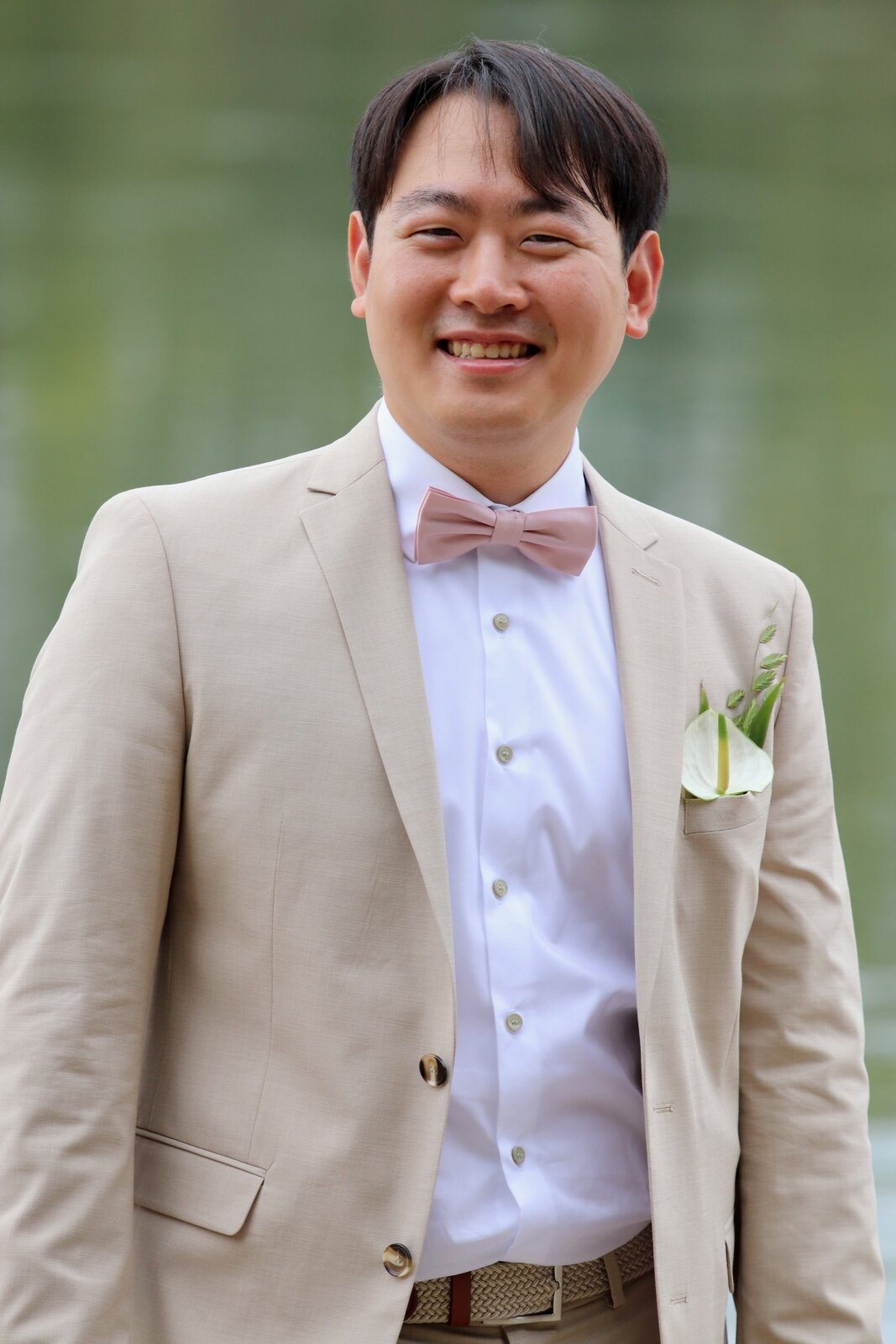 Yongjai smiling in his wedding suit beside the water